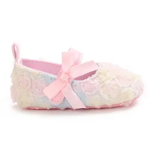 Side view of baby girl Mary Jane shoes featuring floral fabric petals and a pink bow