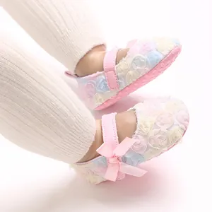 Close-up view of cute pink baby Mary Jane shoes with floral pattern and bow accents.