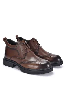 Side view of brown leather men's brogue boots showing intricate wingtip patterns and thick soles