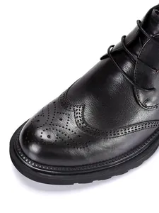 Close-up of black leather men's boots featuring classic brogue wingtip details.