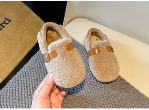 Warm winter children's Sherpa shoes with decorative brown leather buckle strap detail.