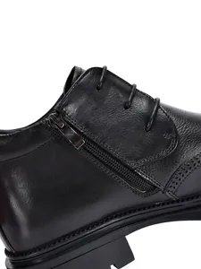 Close-up detail of black leather men's boot with side zipper and brogue patterns