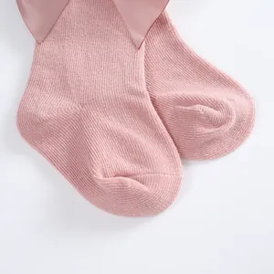 Detail of soft pink Spanish style cotton socks for babies featuring a large satin bow accent.
