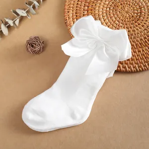 Detalle de calcetines altos blancos para niños con un gran lazo de satén decorativo