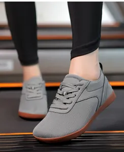 Gros plan de chaussures de marche en maille grise portées sur un tapis de course en salle.
