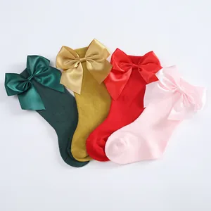 Detail view of colorful children's knee-high socks with large satin ribbon bows.
