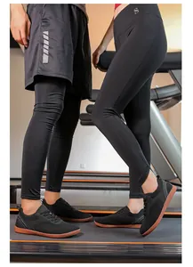 Un couple portant des baskets de marche noires en maille sur des tapis de course.