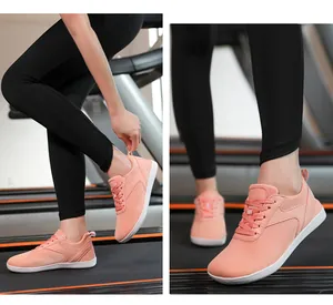 Détail montrant des baskets en maille rose respirantes portées sur un tapis de course.