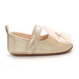 Nahaufnahme goldener Baby-Prinzessinnen-Lernlaufschuhe mit großer Spitzenschleife.