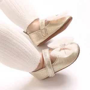 Nahaufnahme von goldenen Lauflernschuhen mit Herz-Strassstein und Spitzenschleife