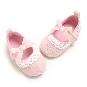 Detaillierte Makroaufnahme von rosa Tweed Babyschuhen mit zarter Spitze und Samtschleifen
