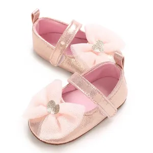 Detailansicht von rosa Prinzessin-Babyschuhen mit großer Spitzenschleife und Glitzerherz
