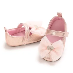 Nahaufnahme rosa glitzernder Lauflernschuhe für Babys mit Spitzenschleife und Herz