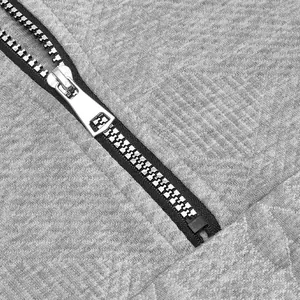 Primer plano de una cremallera metálica de calidad en una sudadera gris con capucha