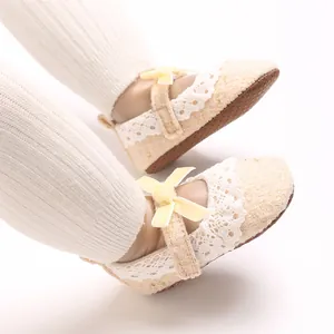Nahaufnahme von beigen Baby-Prinzessinnenschuhen mit Spitze und gelben Schleifen