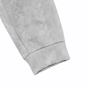 Primer plano detallado de la textura jacquard con patrón de hojas en la manga de la sudadera