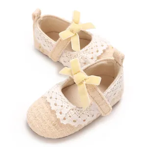 Detailansicht cremefarbener Babyschuhe für Mädchen mit Spitze und gelber Schleife