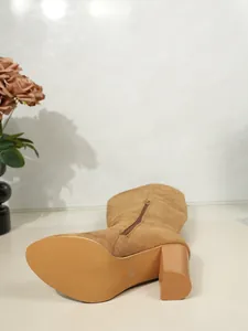 Close-up of suede chunky heel thigh-high boot showing the textured sole and side zipper