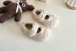 Nahaufnahme von cremefarbenen flauschigen Kinderschuhen mit Doppelschleife in gemütlichem Ambiente