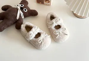 Nahaufnahme süßer cremefarbener Pelzschuhe für Kinder mit zarten Doppelschleifendetails.