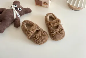 Nahaufnahme der süßen braunen Plüschschuhe für Kinder mit schicken doppelten Schleifen