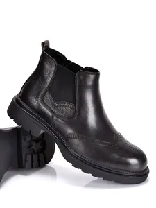 Nahaufnahme von schwarzen Chelsea-Boots aus Leder mit eleganten Brogue-Verzierungen