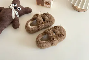 Nahaufnahme von flauschigen braunen Kinderschuhen mit eleganten Schleifenakzenten und weicher Textur