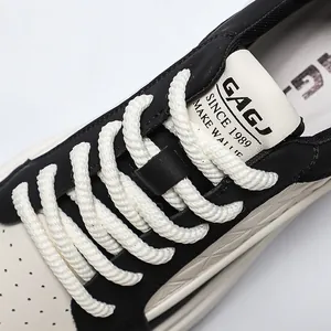 Detailopname van dikke touwveters en logo op zwart-witte leren sneakers voor heren