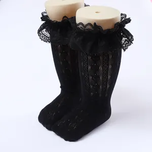 Close-up of children's black lace ruffle knee-high socks with intricate knit patterns.
