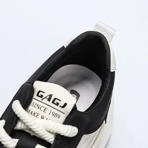 Close-up detail van de kraag en tong van een zwart-witte sneaker met het merklogo van GAGJ.