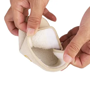 Close-up view of the soft white fleece lining and Velcro strap on beige baby winter boots.