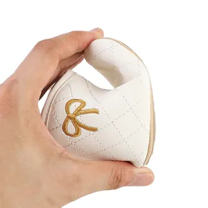 Close-up view showing the high flexibility of a white baby shoe with a gold bow