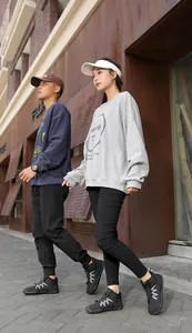 Full view of couple models wearing black warm snow boots in a stylish outdoor street setting.