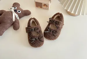 Nahaufnahme der weichen braunen Plüschschuhe mit doppeltem Schleifendesign für Mädchen