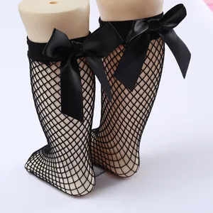 Close-up detail of black fishnet socks with decorative satin bows for girls Lolita style