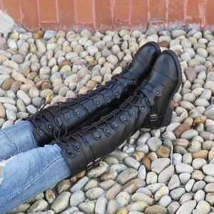 Gros plan de bottes de cavalier noires à lacets avec boucles et rivets sur des galets