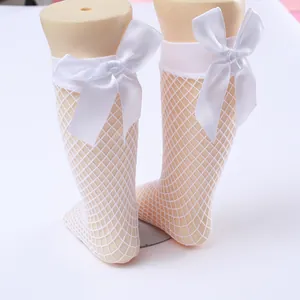 Close-up view of white fishnet knee-high socks for girls featuring large satin bows decoration