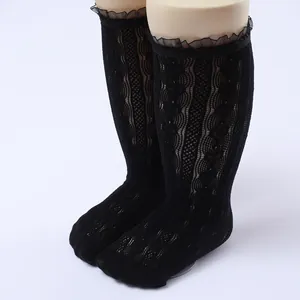 Close-up detail of girls' black lace mesh knee-high socks featuring ruffled lace trim