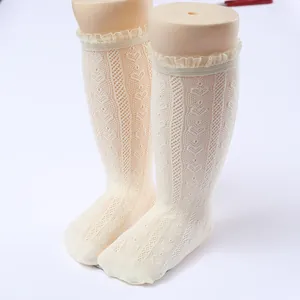 Close-up detail view of white lace hollow-out knee high socks for baby girls princess style