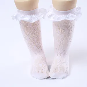 Close-up of white lace ruffle knee-high socks for girls with intricate floral mesh pattern.