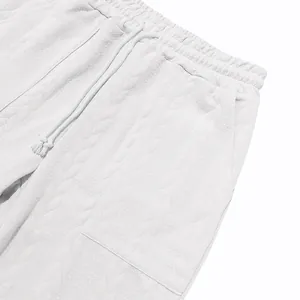 Detailed close-up view showing the white jacquard textured fabric on men's sweatpants
