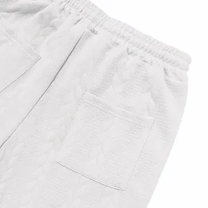Close-up detail of white jacquard textured fabric and patch pocket on men's track pants