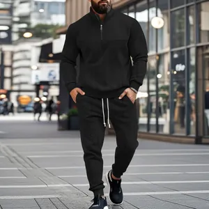 Full view of a man wearing a black textured tracksuit set in an urban street setting.