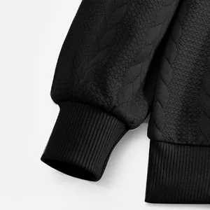 Primer plano de sudadera negra con patrón jacquard de hojas y puños de canalé