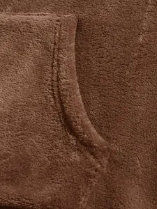 Close-up of soft brown coral velvet fabric and pocket stitching on a men's oversized hoodie.