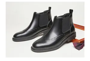 Détail de bottines Chelsea en cuir noir avec des perforations brogue classiques pour hommes.