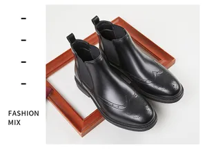 Vue rapprochée de bottines Chelsea pour hommes en cuir noir avec des détails perforés brogue.