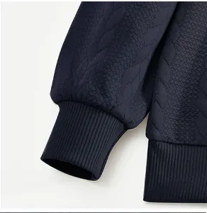 Primer plano detallado del tejido jacquard azul marino y el puño acanalado de sudadera