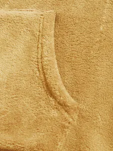 Macro detail view of soft yellow coral fleece fabric texture on garment pocket edge