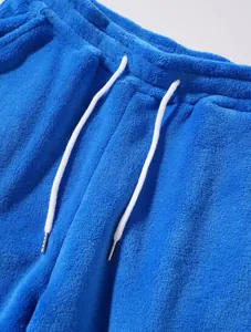 Gedetailleerde opname van de koraalfleece textuur en het witte trekkoord op de blauwe korte broek